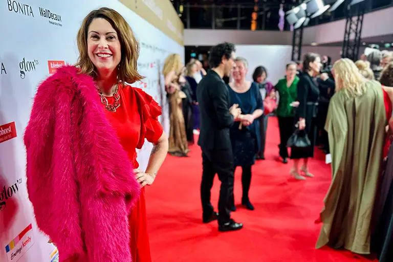 Madita van Hülsen im roten Kleid mit pinkem Federmantel auf dem roten Teppich einer Abendveranstaltung