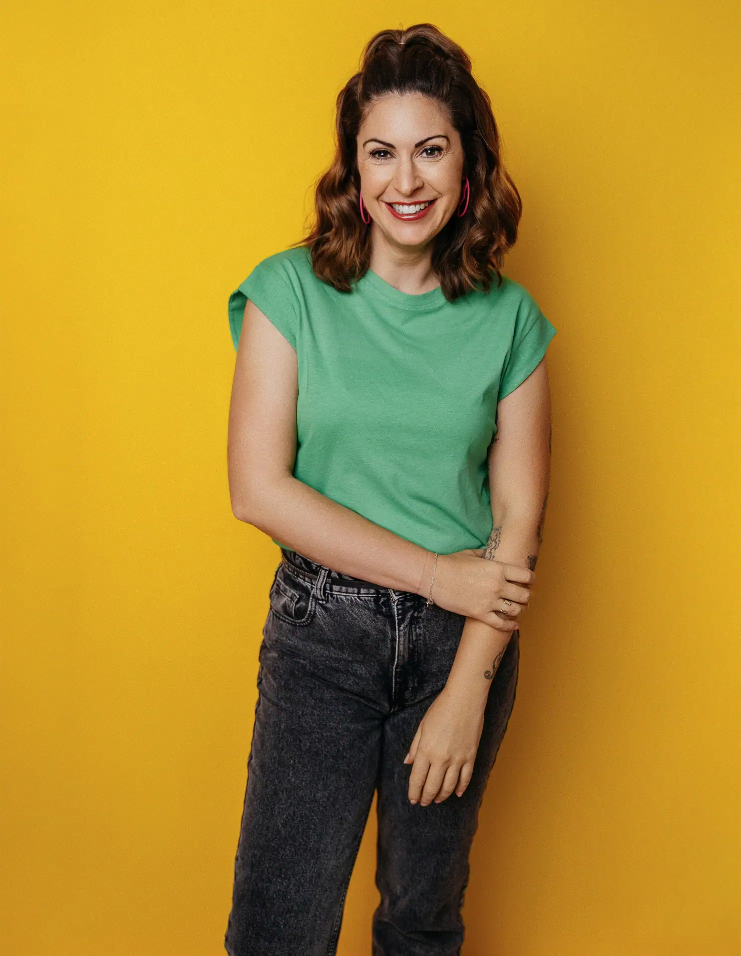 Moderatorin Madita van Hülsen im grünen Shirt und dunkler Jeans vor gelbem Hintergrund