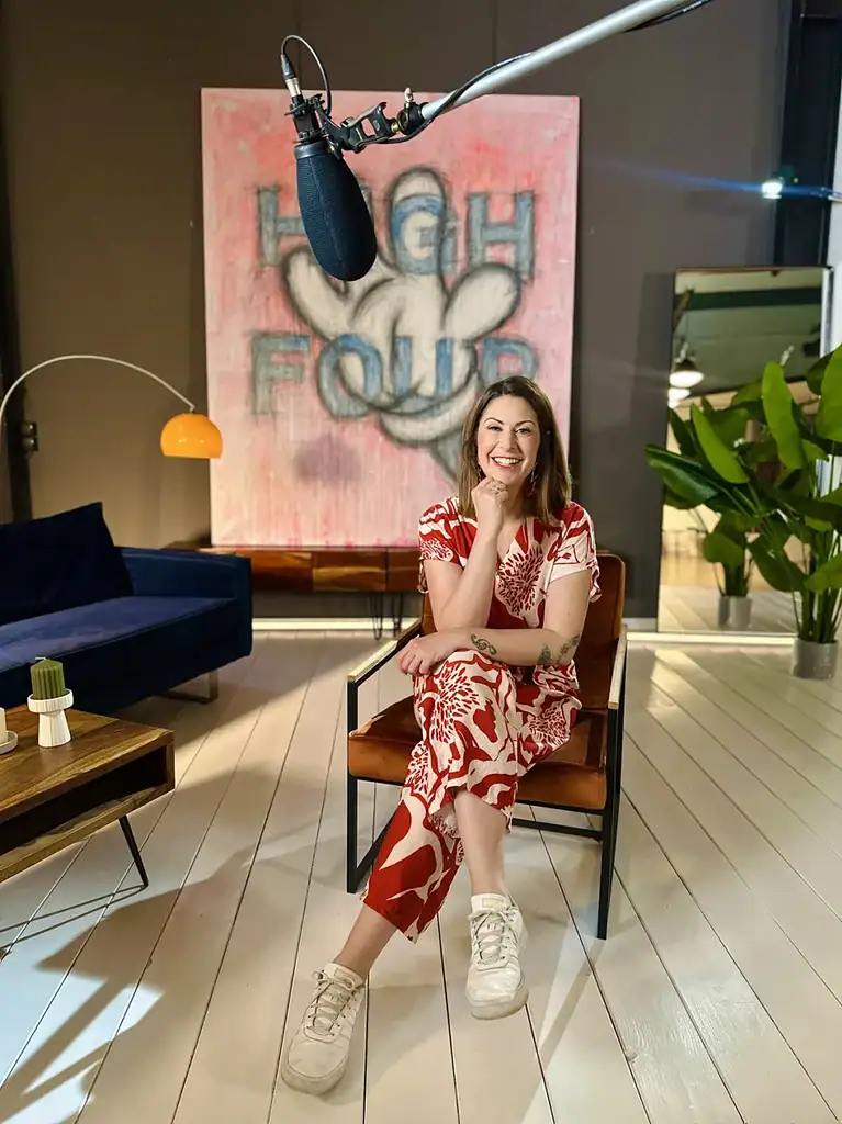 Moderatorin Madita van Hülsen sitzt im rot-weißen Blumenkleid in einem Sessel, über ihr ein Studiomikrofon
