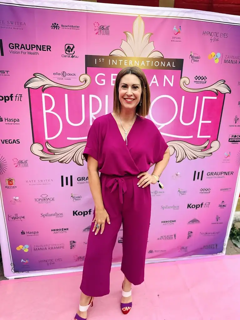 Moderatorin Madita van Hülsen im beerenfarbenen Jumpsuit vor der Fotowand einer Abendveranstaltung
