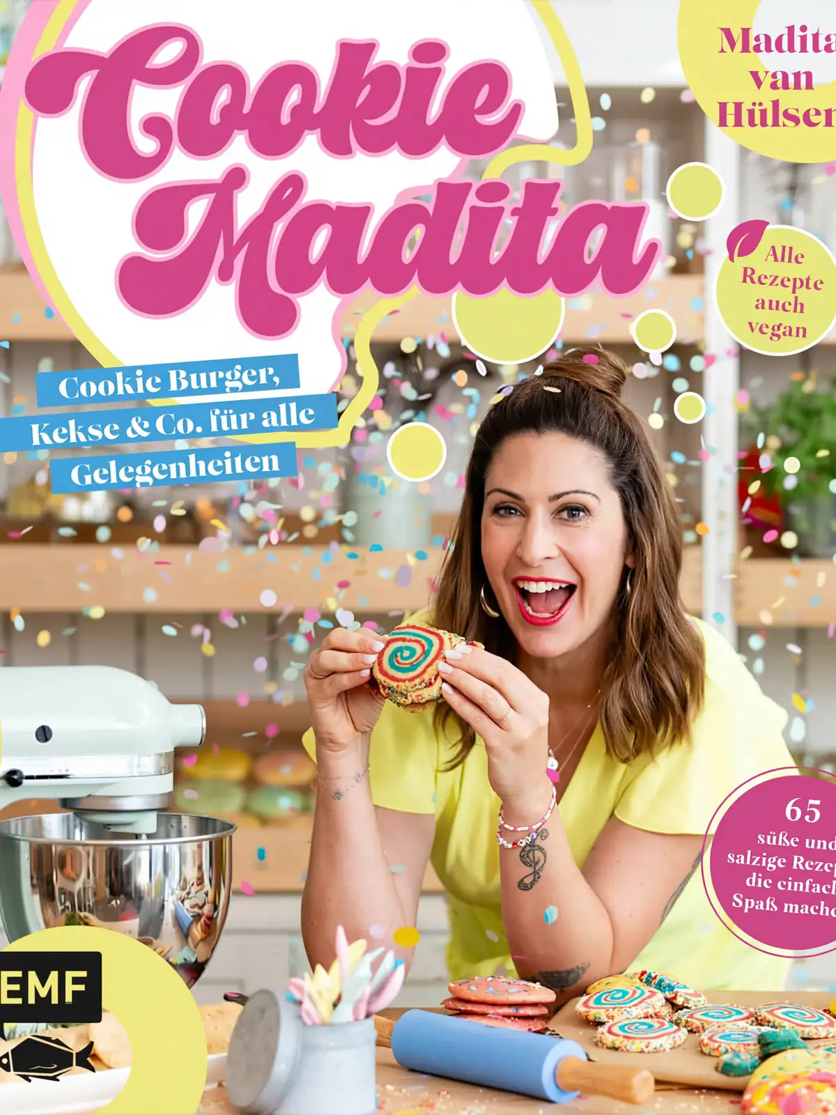 Buchcover Cookie Madita: Madita van Hülsen hält in einer Küche einen bunten Regenbogen-Cookie in die Kamera, Konfetti fliegt durchs Bild
