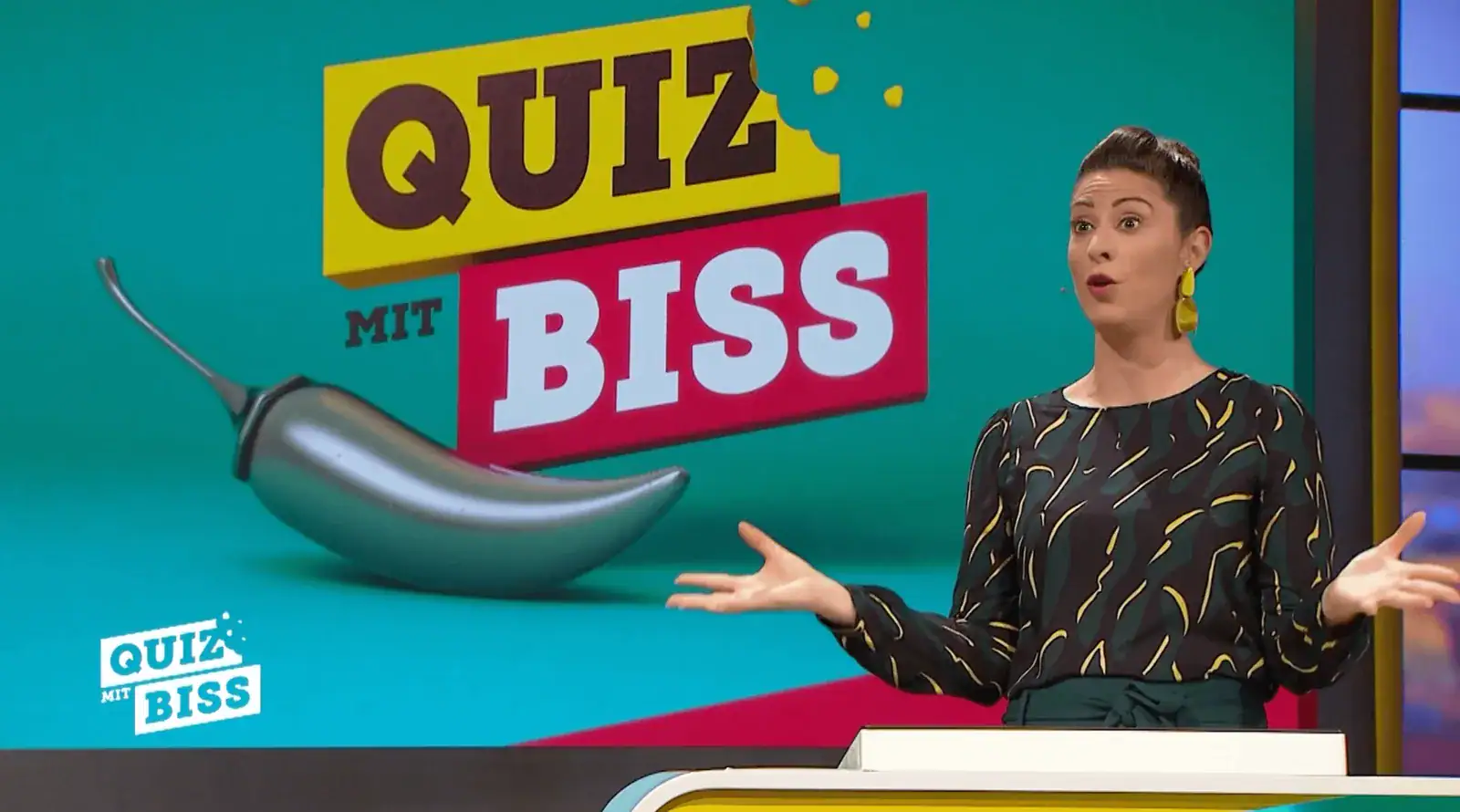 Madita van Hülsen moderiert im Studio ihrer Show Quiz mit Biss, neben ihr das Sendungslogo