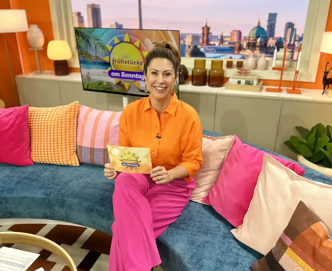 Madita van Hülsen sitzt im Studio des SAT.1-Frühstücksfernsehens auf dem Sofa vor dem Berliner Panorama