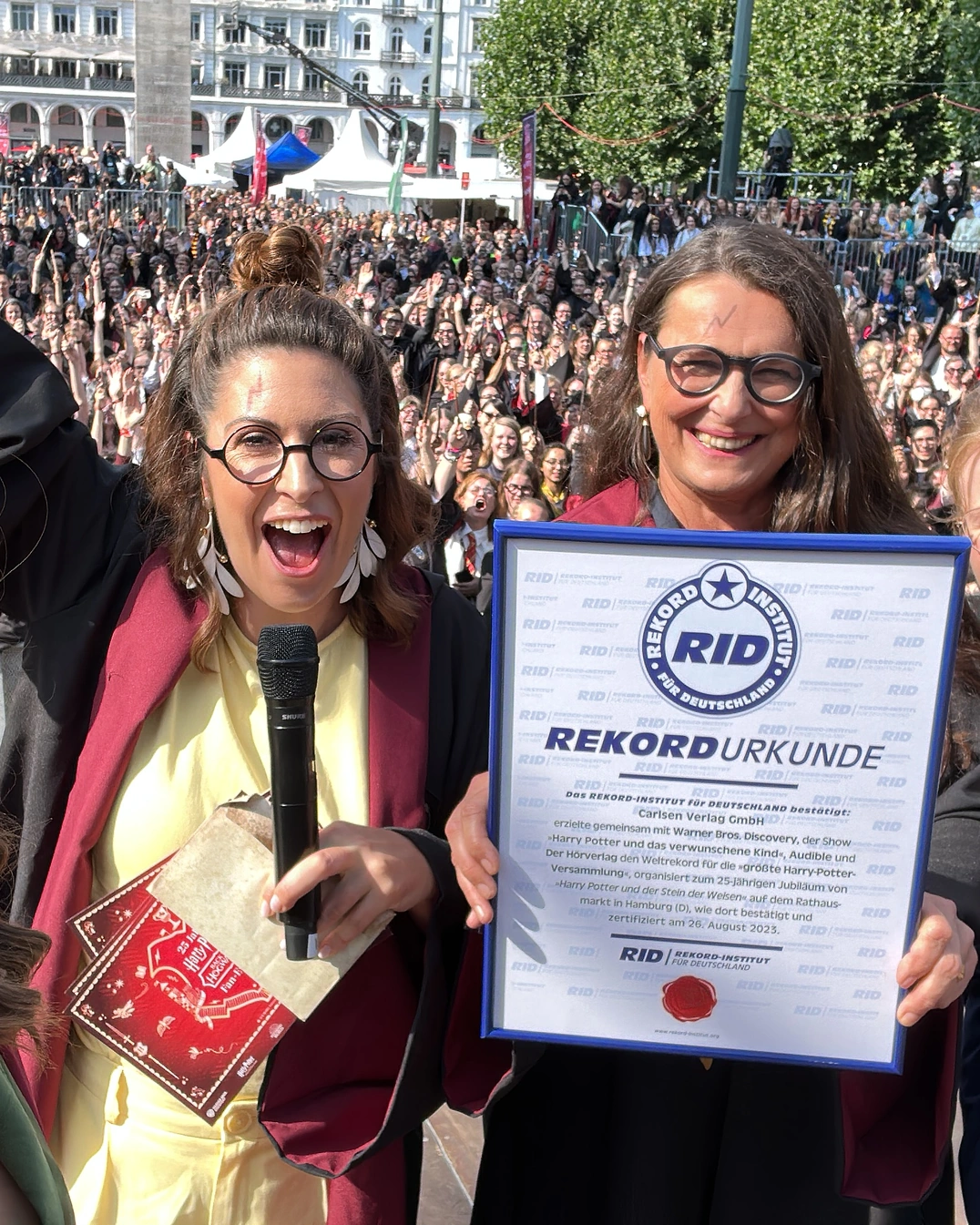 Madita van Hülsen mit Mikrofon auf einer Bühne, neben ihr eine Frau mit Rekordurkunde, dahinter ein großes Publikum